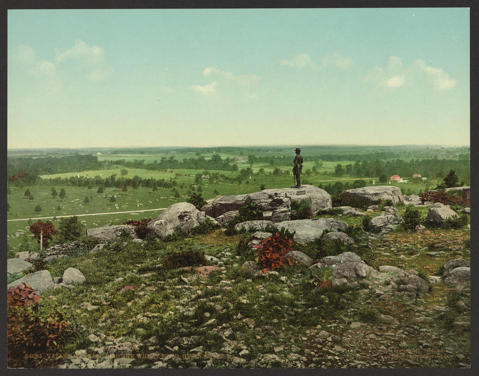 Hand-colored photograph of rocky battlefield overlook with soldier statue — historic photograph