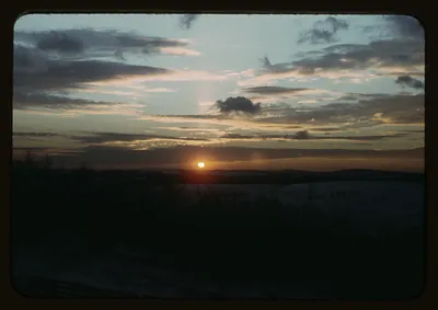 Sunset over dark horizon with scattered clouds