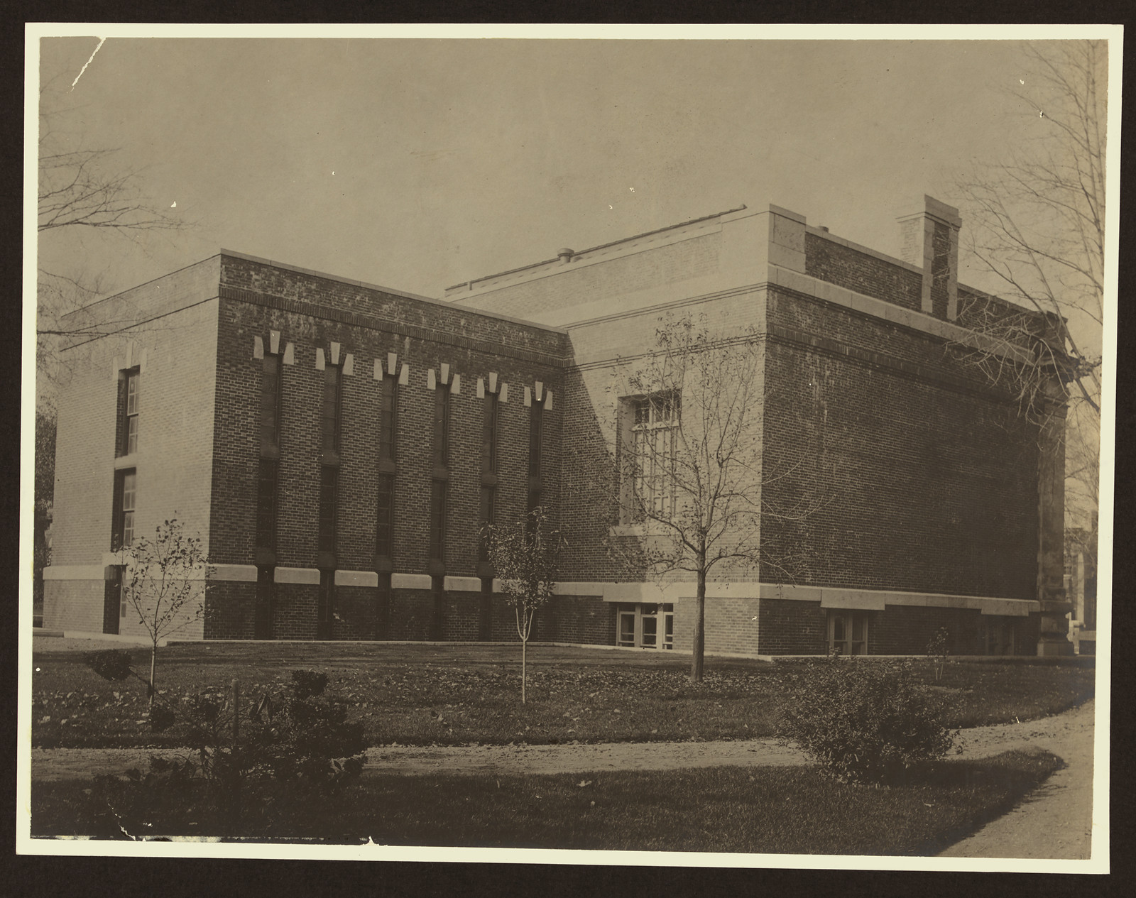 Brick building with vertical pilasters and lawn — historic image