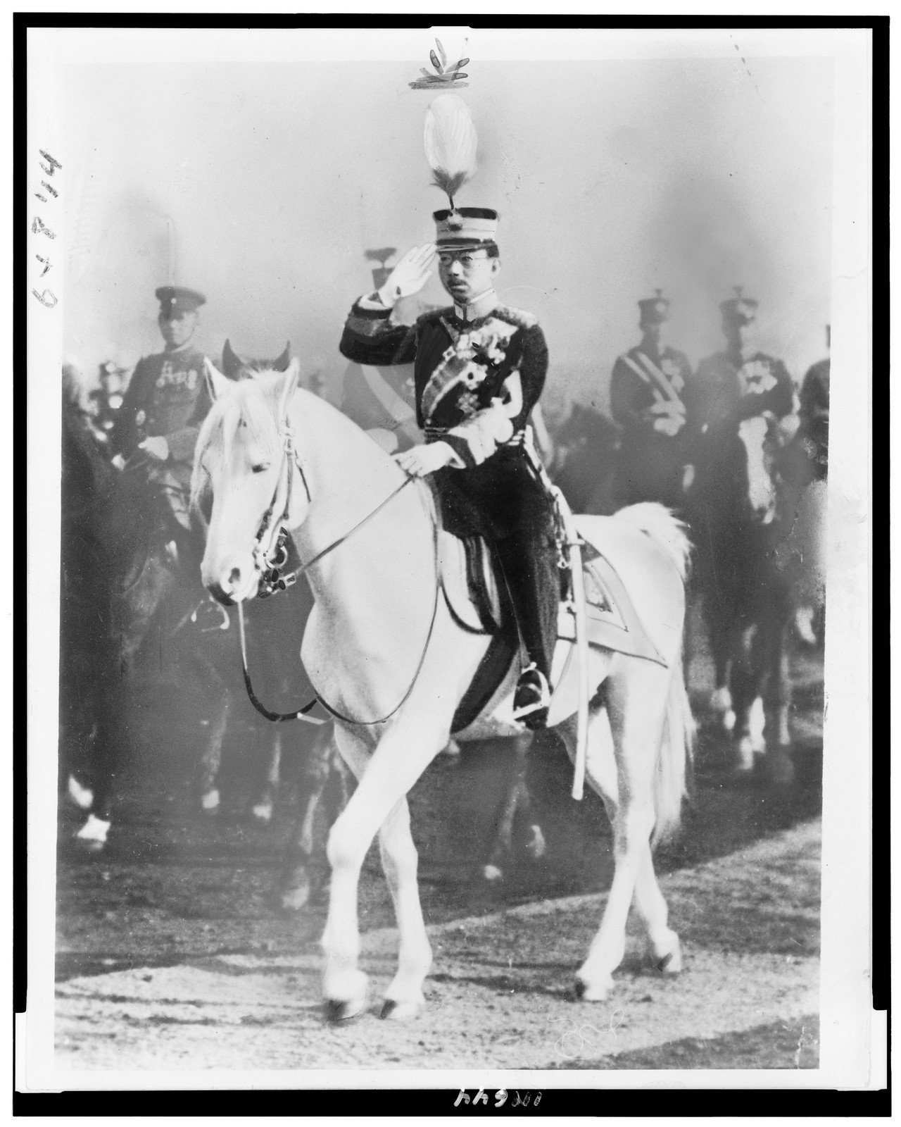 [Japan's Emperor Hirohito on horseback, saluting, facing left, with Japanese officers also on horseback, reviewing troops in northern China, at Yoyogi parade ground] — historic photograph