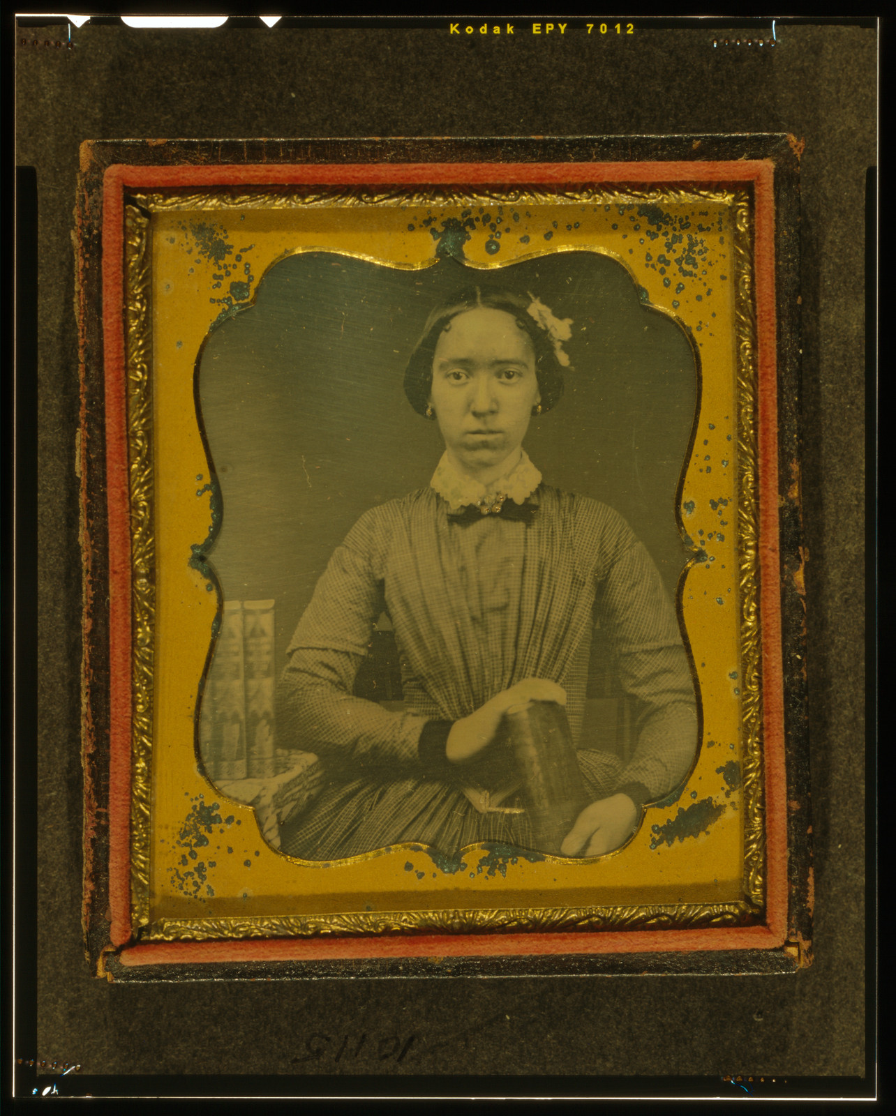 [Unidentified woman holding book, with books on table to her right], [between 1840 and 1860] — historic photograph