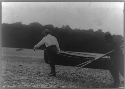 [Theodore Roosevelt carrying boat with another man while a third carries oars]