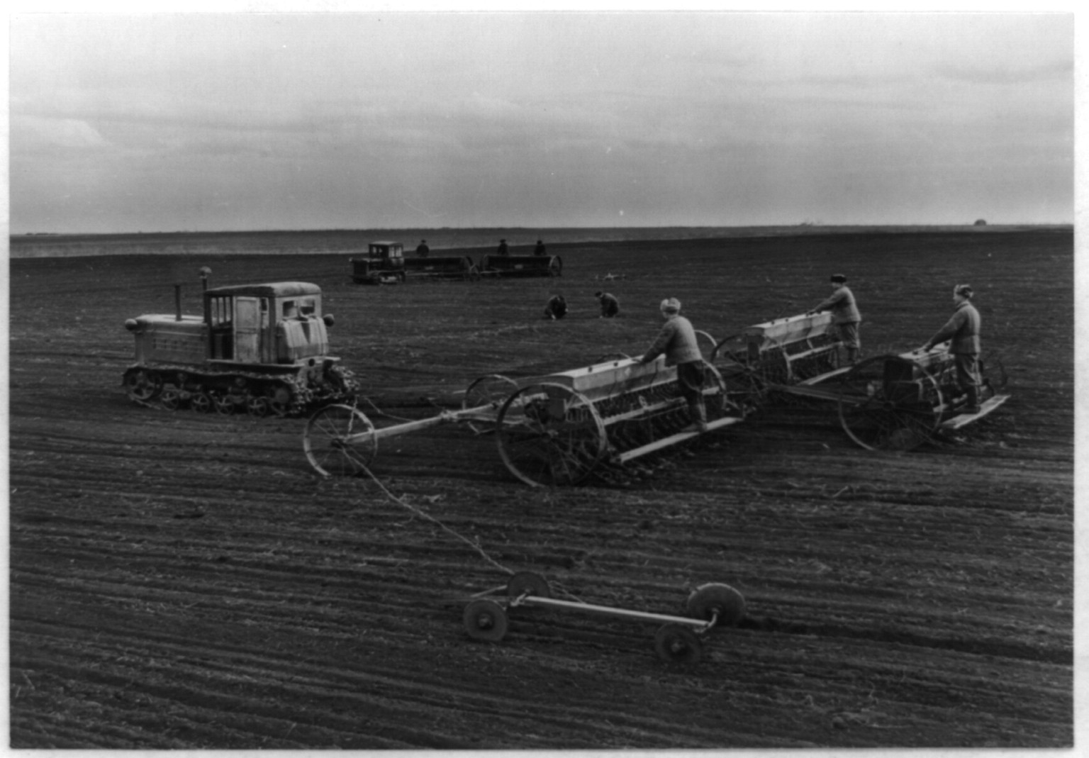 [Men using tractors and machinery to plant seeds in field in the Soviet Union], [1955] — historic photograph