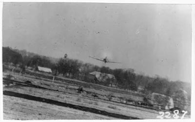 [German airplane in flight over open field during World War II]