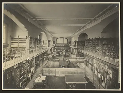 Library reading room with galleried bookshelves and long tables