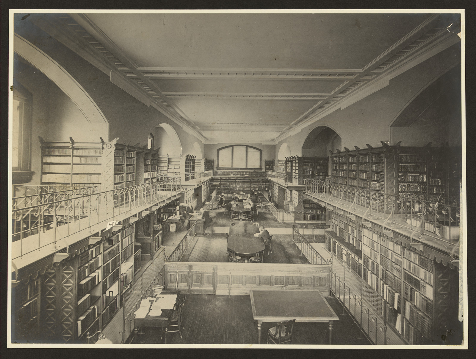 Library reading room with galleried bookshelves and long tables — historic image