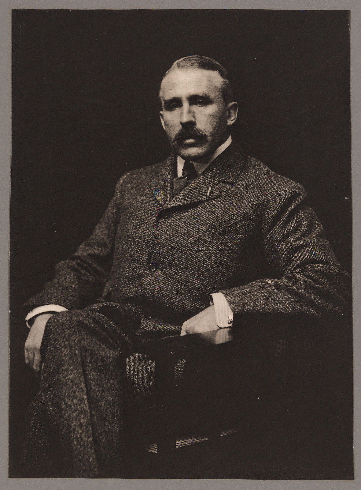 Seated man in tweed suit, studio portrait — historic image