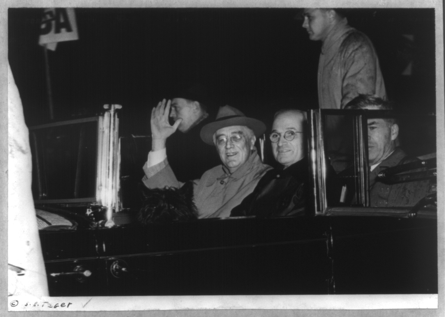 [Franklin D. Roosevelt, bust, seated in car, waving, facing slightly left, with Harry Truman and unidentified person returning to Washington on Nov. 10, 1944], c1944. — historic photograph