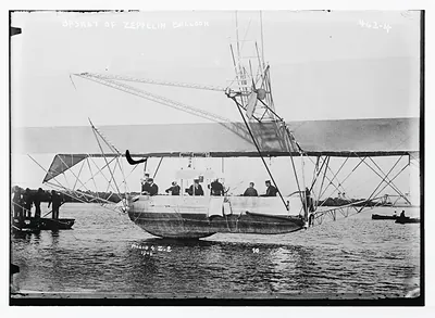 Men inside basket of Zeppelin airship, on water