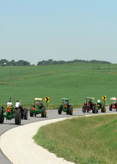Vintage tractors in a line on a rural road