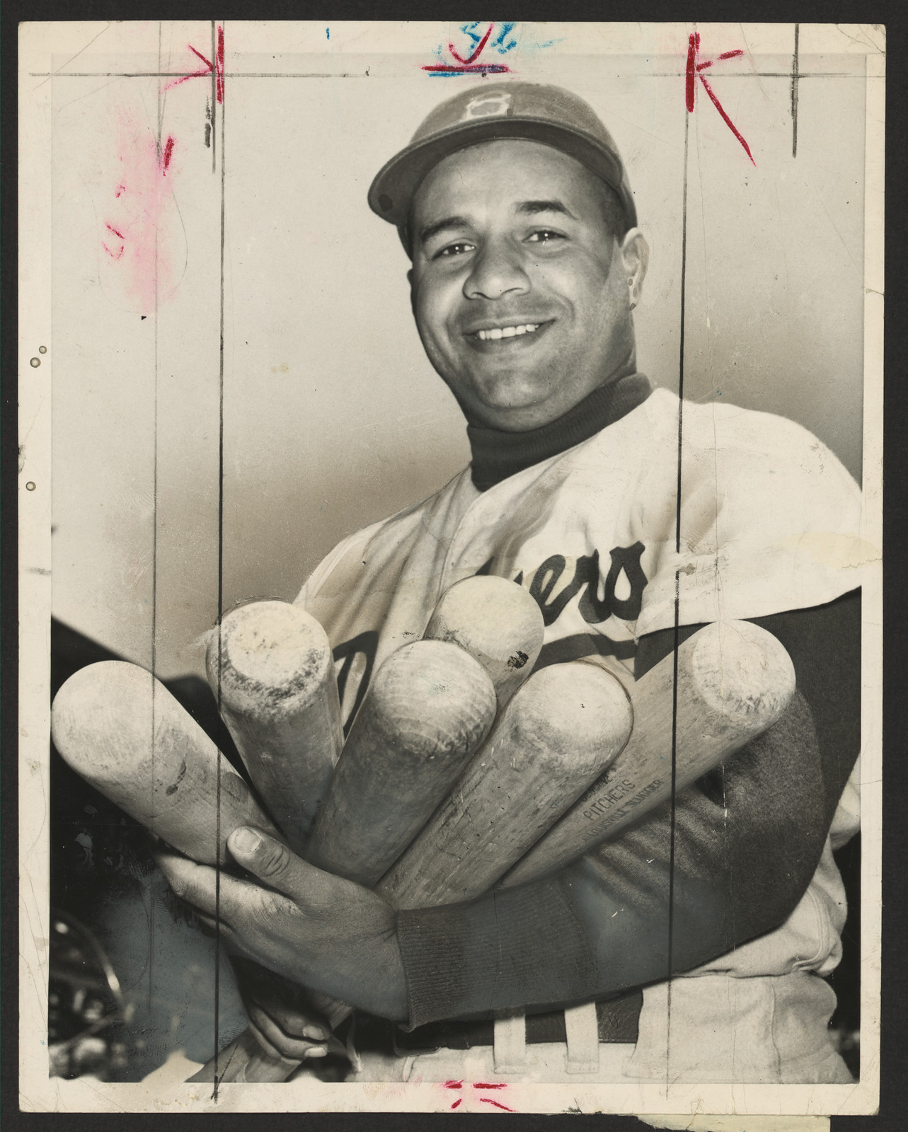 Smiling baseball player holding several bats, photograph — historic photograph