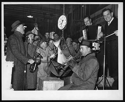 Musicians playing trumpet, saxophone and accordion beside a hanging scale