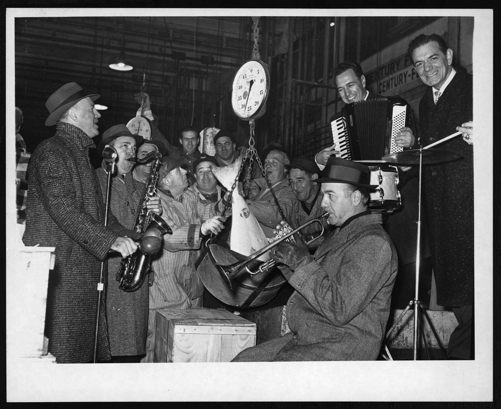 Musicians playing trumpet, saxophone and accordion beside a hanging scale — historic image
