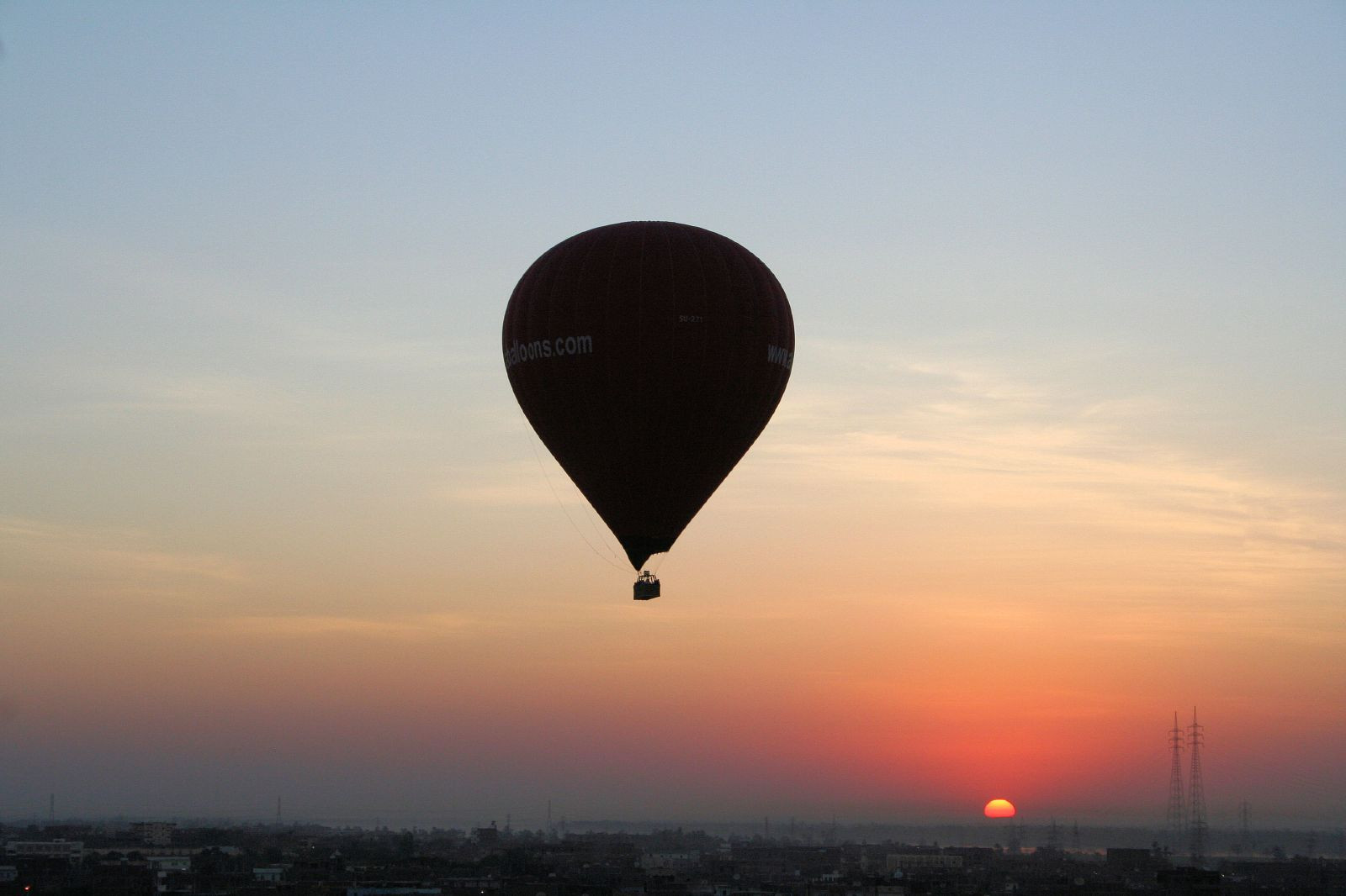 Hot air balloon silhouetted against a sunrise over a city — historic image