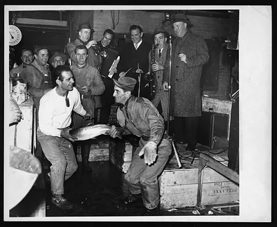 Men holding a large fish at a fish market