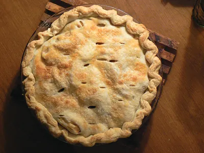 Baked pie with slashed crust on a wooden table