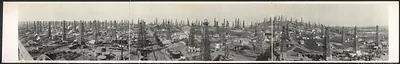 Panoramic view of oil derricks and storage tanks