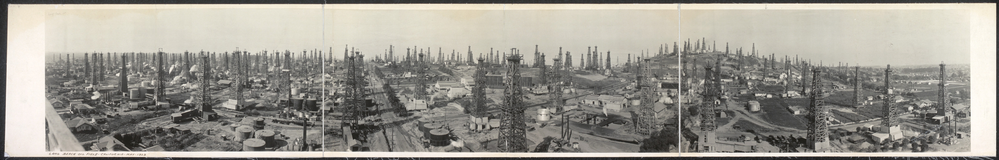 Panoramic view of oil derricks and storage tanks — historic image