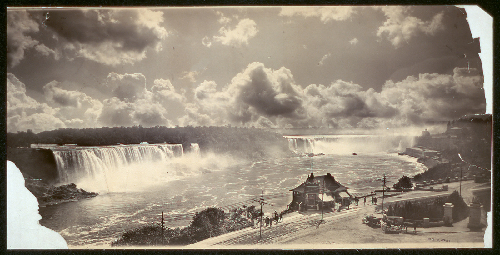 Niagara Falls with cloud-filled sky and a riverside pavilion — historic image