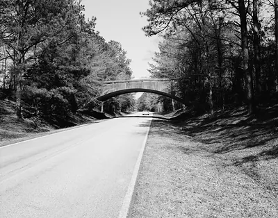 Black and white view of parkway road under concrete arch bridge