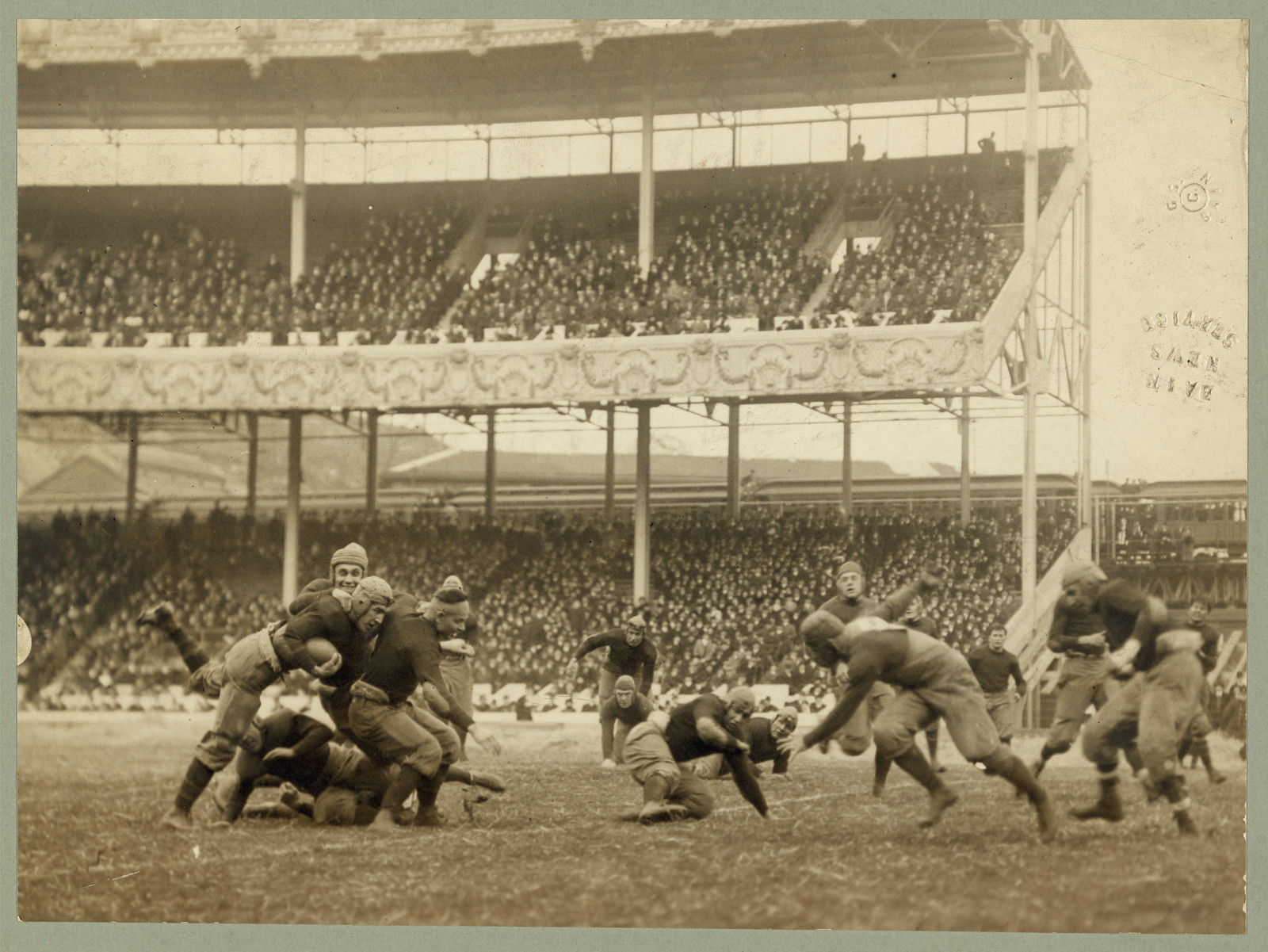 Football players in action before a crowded stadium, 1916 — historic image