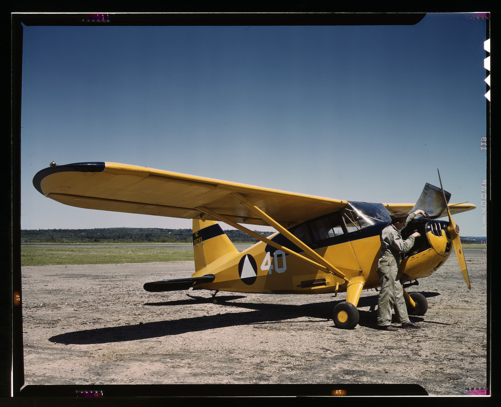 Civil Air Patrol yellow monoplane with pilot on airfield — historic image