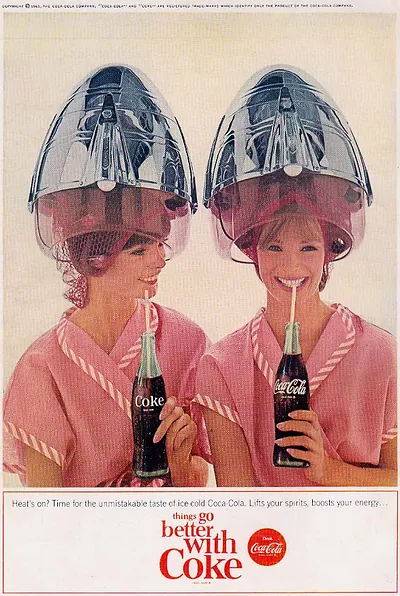 Coca-Cola magazine advertisement with two women under hair dryers