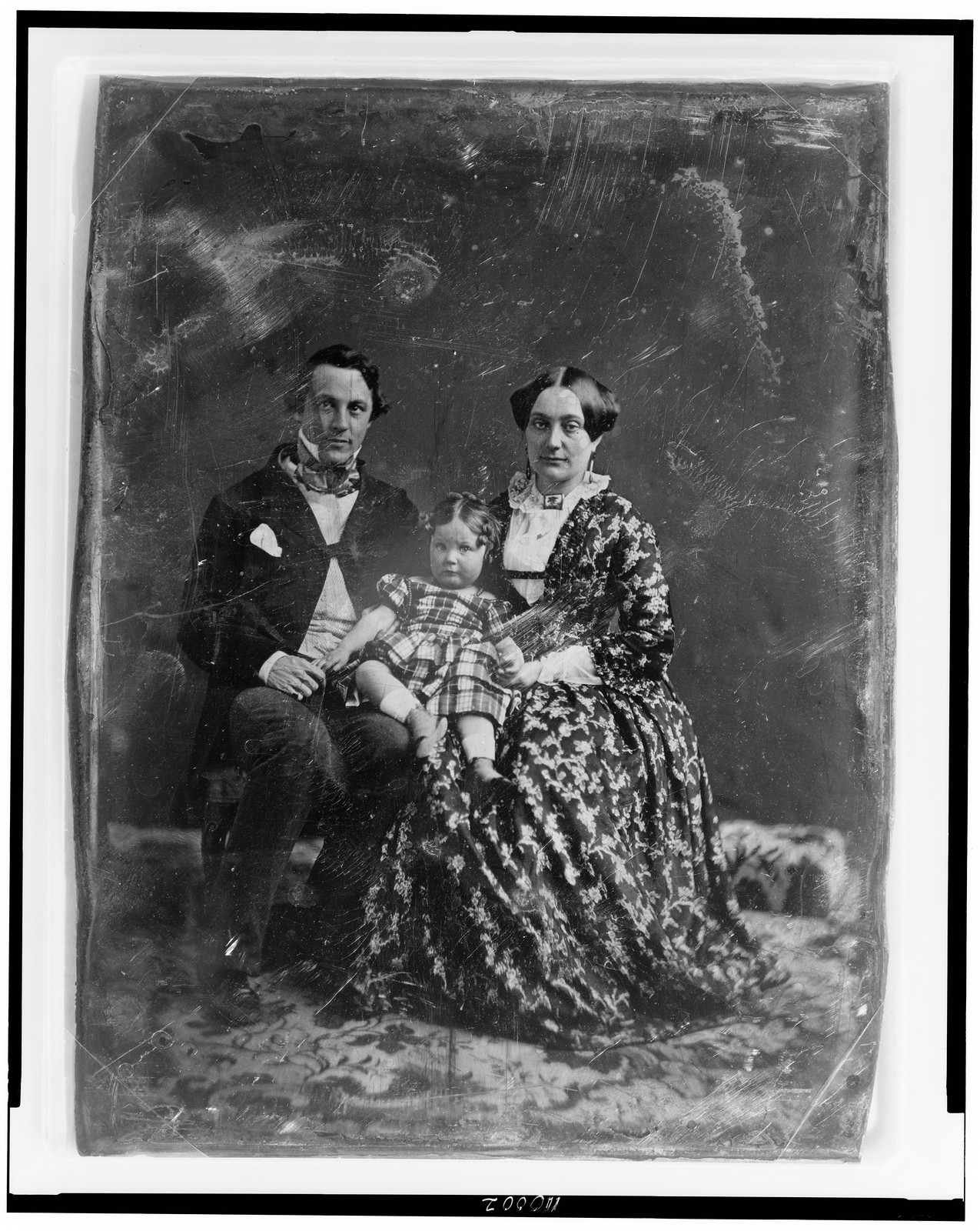 Seated man, woman and child, early studio daguerreotype portrait, 1844 — historic photograph