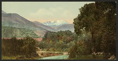 Snow-capped mountain peak above a wooded river valley