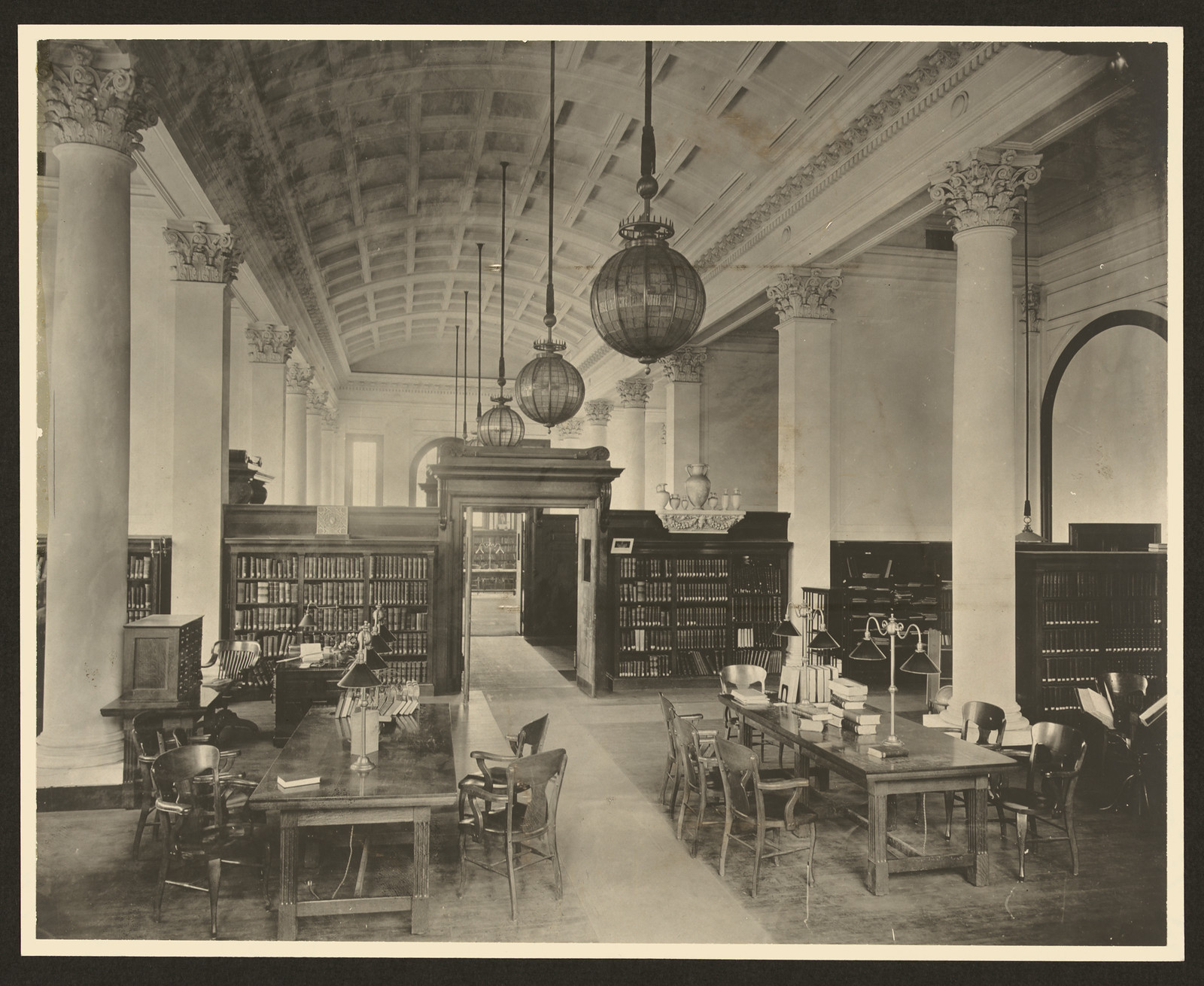 Reading room with columns, pendant lamps and bookshelves — historic image