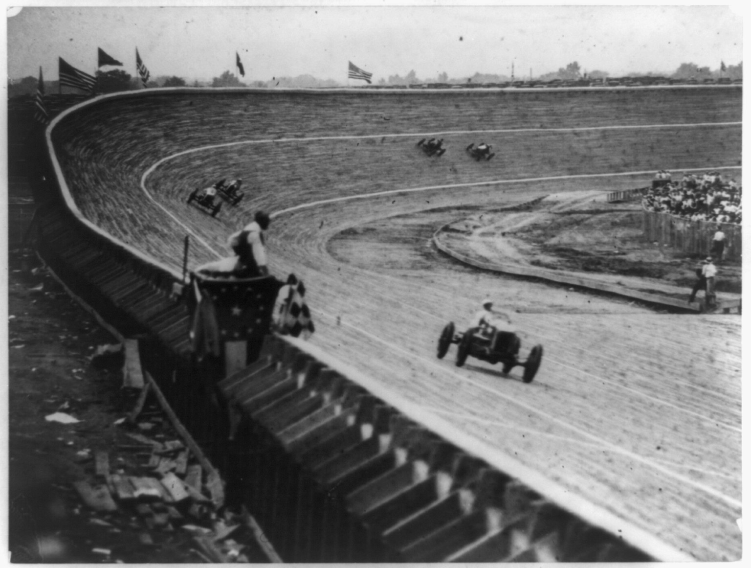 [Automobile racing on curved wood track, probably in or near Washington, D.C., with flag man in foreground], [ca. 1922] — historic photograph