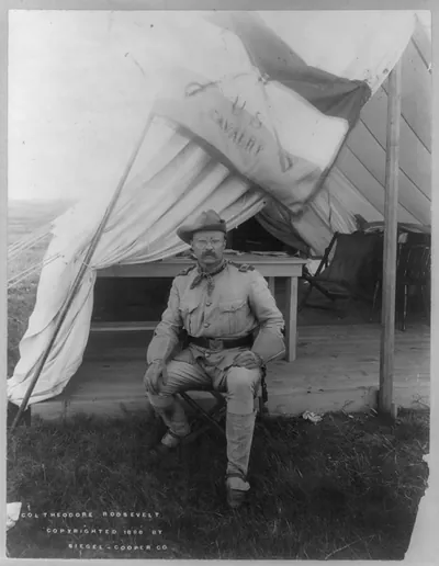 [Theodore Roosevelt, full length, seated at entrance to tent, facing front, in uniform]