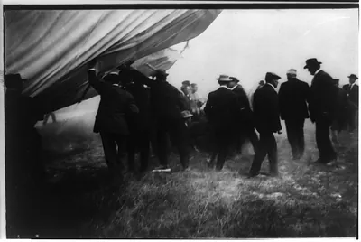Spectators lifting the aeroplane from the bodies of the injured men