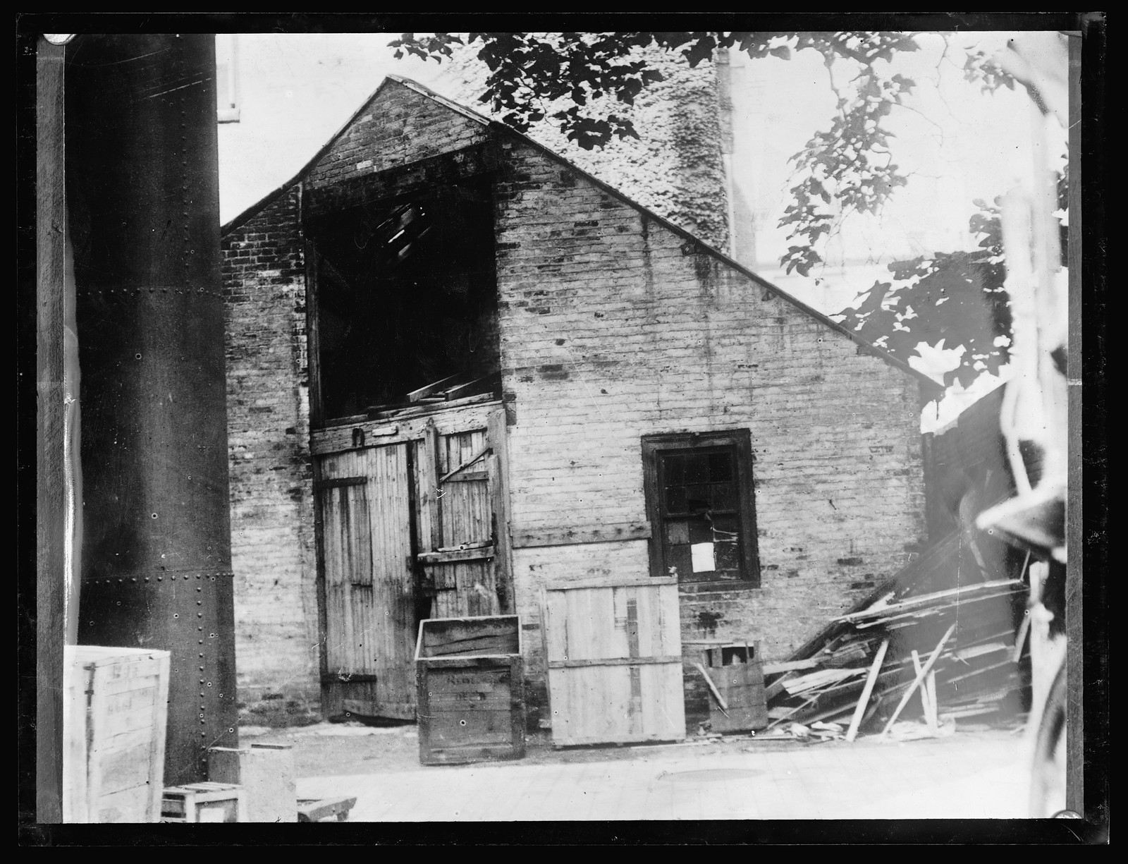 Brick building with wooden doors and packing crates — historic image