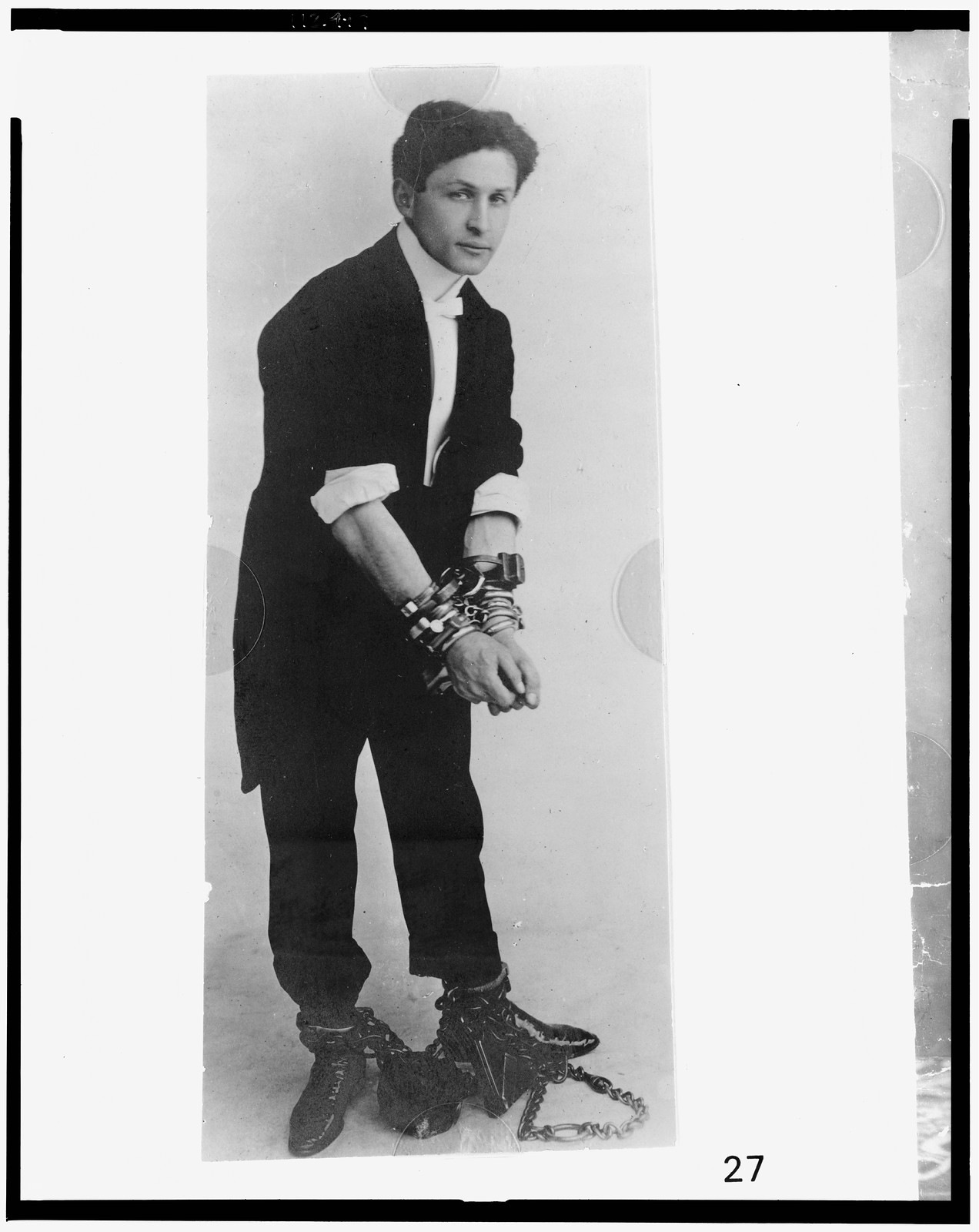 [Harry Houdini, full-length portrait, standing, facing right, in chains], c1905. — historic photograph