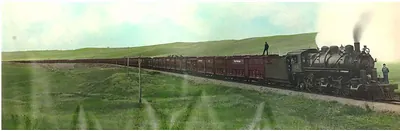 Hand-colored photograph of steam locomotive hauling freight train