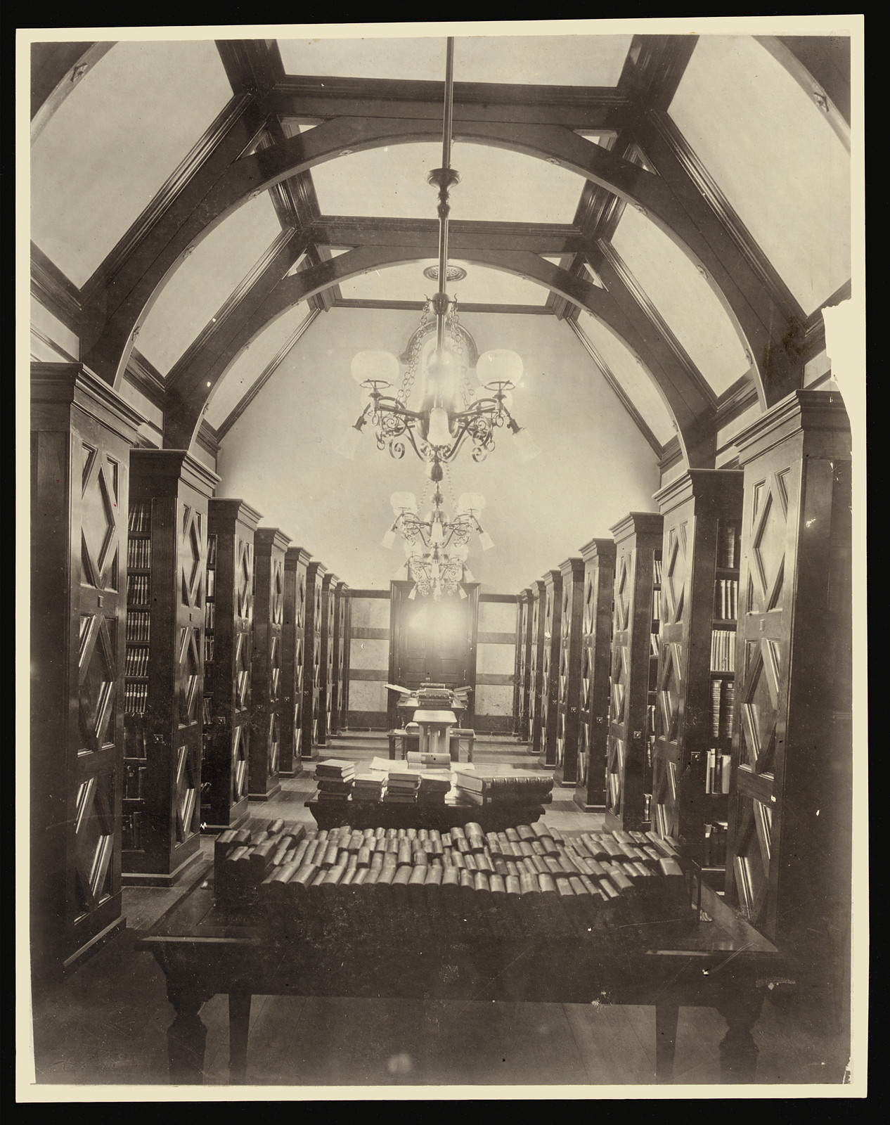 Library bookroom with vaulted ceiling, tall shelves and chandelier — historic image