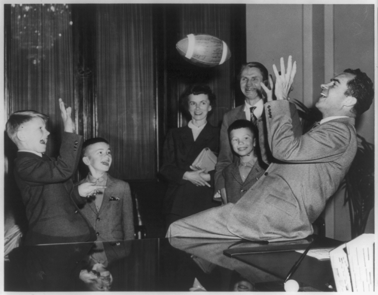 [Richard Milhaus Nixon, 1913-, seated, at desk in Capitol, playing football with Andrus Suritis, one millionth refugee relocated by an international welfare organization] — historic photograph