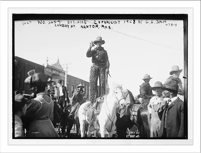 Cowboy standing in saddle on horse, Newton, Mass.