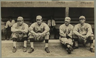 Four Red Sox players seated on dugout bench, names written above