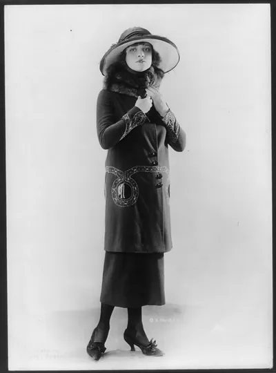 [Woman modeling hat and suit with long coat and fur collar]