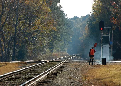 Flagman with stop sign beside railway tracks