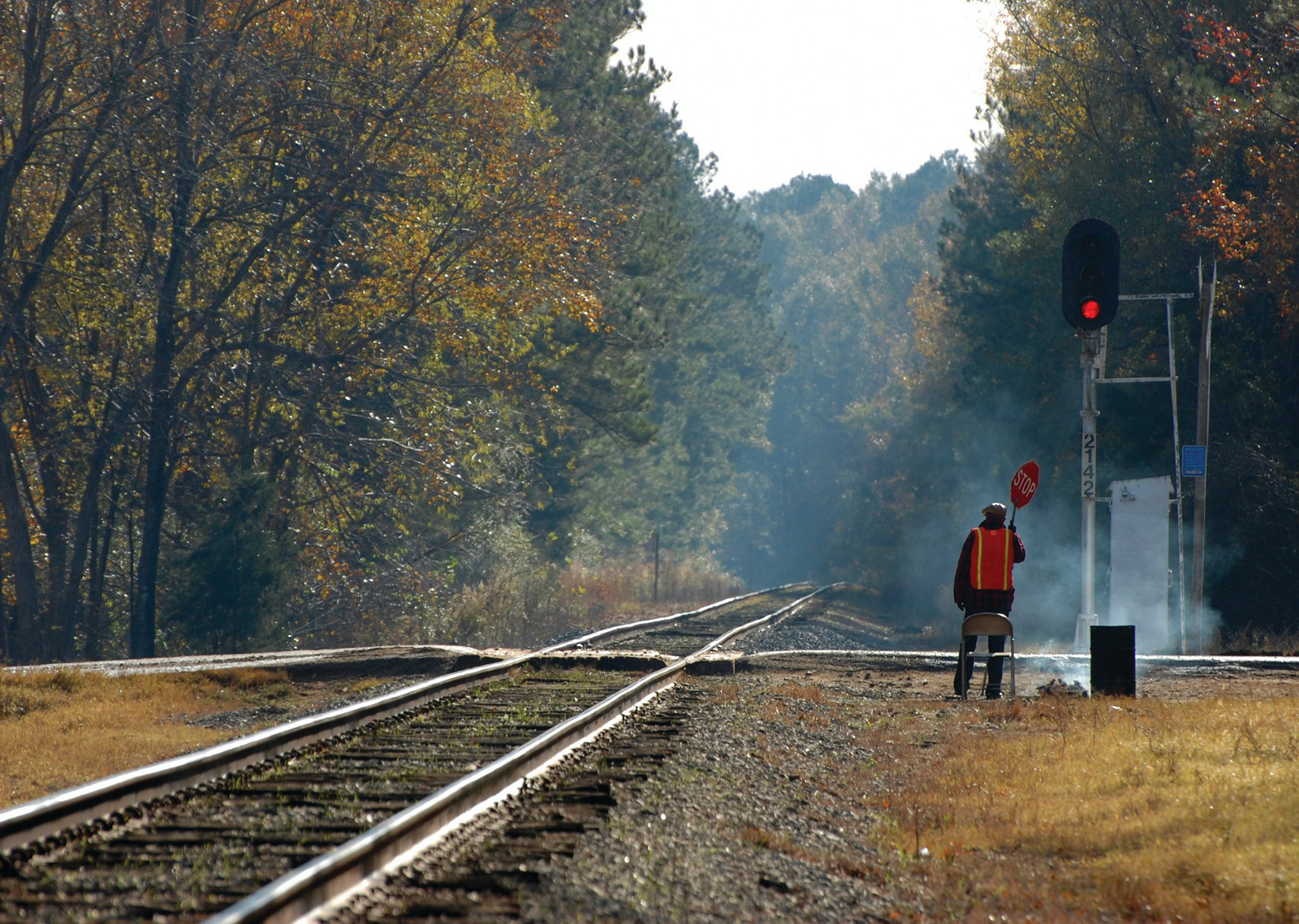 Flagman with stop sign beside railway tracks — historic image