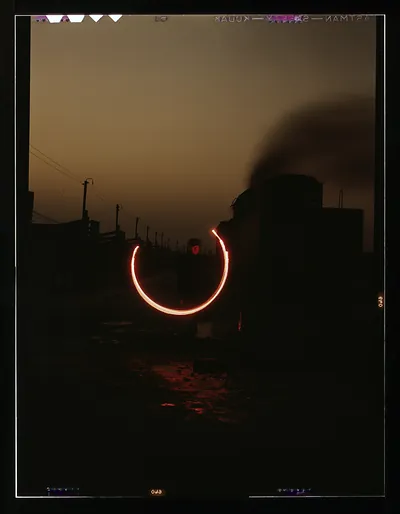 Railroad worker swinging lantern at dusk beside locomotive