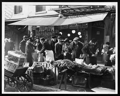 Customers buying vegetables at a city street market