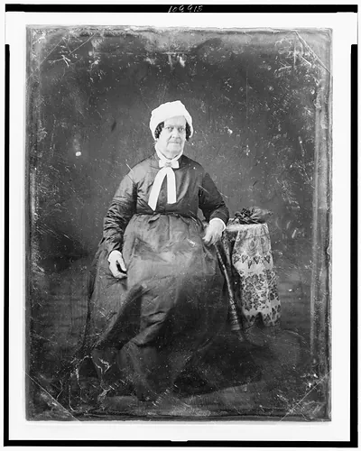 Seated elderly woman in white cap and dark dress