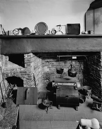 Historic kitchen hearth with hanging kettles and iron stove