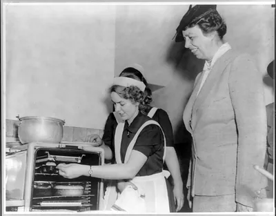 [Eleanor (Roosevelt) Roosevelt 1884-1962: watching Girl Scouts baking, left profile]