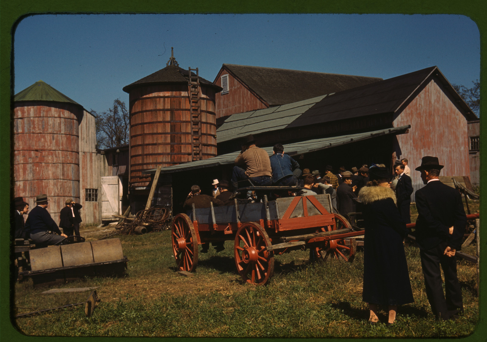 Crowd gathered at farm with red wagon and silos — historic image
