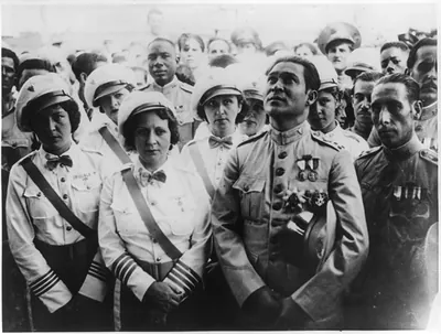 [Cuban War Minister Fulgencio Batista with his wife and officers of her military womens' legion, Cuba, 1935-36]
